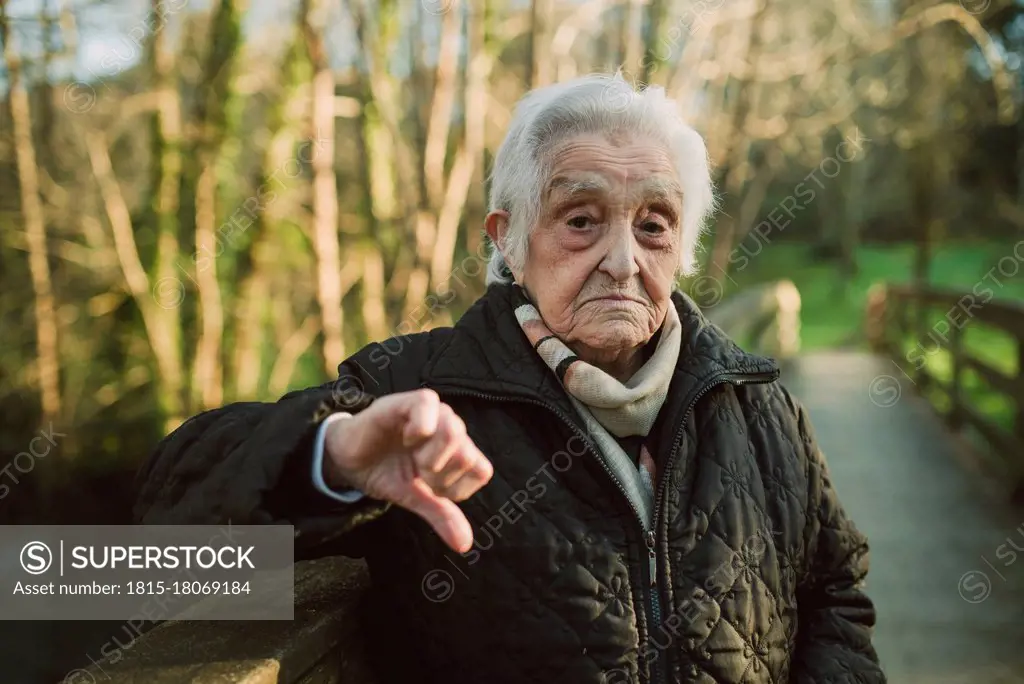 Displeased senior woman showing thumbs down gesture during winter