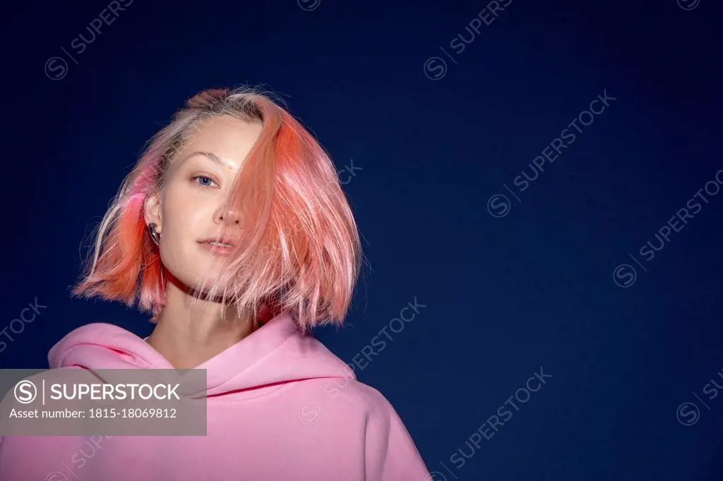 Portrait of young woman with pink hair wearing pink hooded shirt at dusk