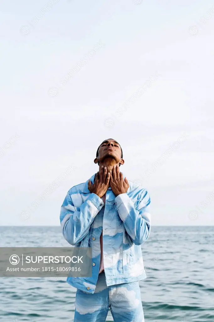 Man with eyes closed standing against sky