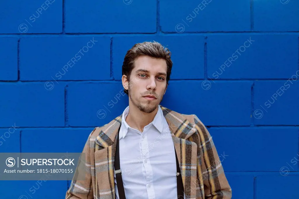 Portrait of stylish man against blue wall