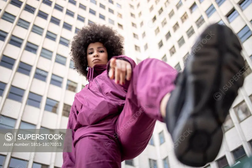 Fashionable young woman with cool attitude gesturing against building exterior