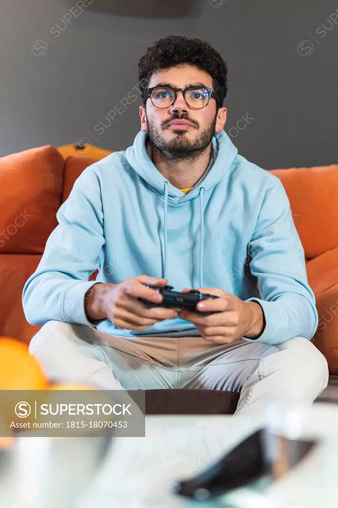 Concentrated young man playing video game in living room