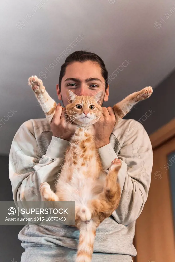 Young man playing with cat at home