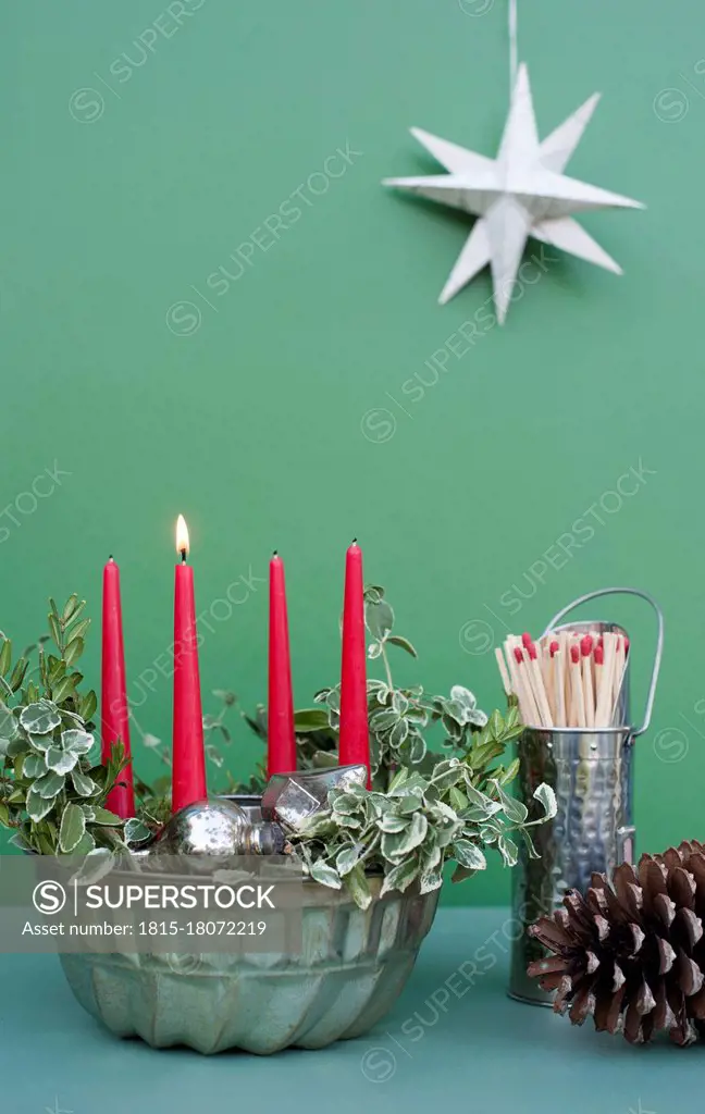 Studio shot of DIY Advent decorations including candles, twigs, pine cone, matches and baking pan