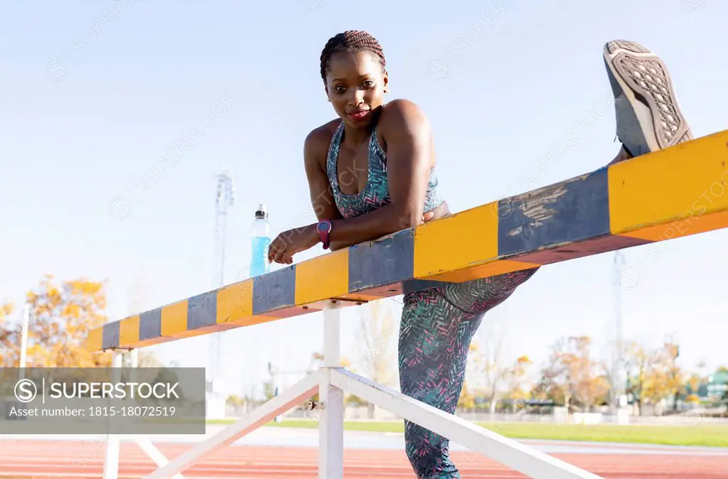 Female athlete with cool attitude stretching on balance beam during sunny day