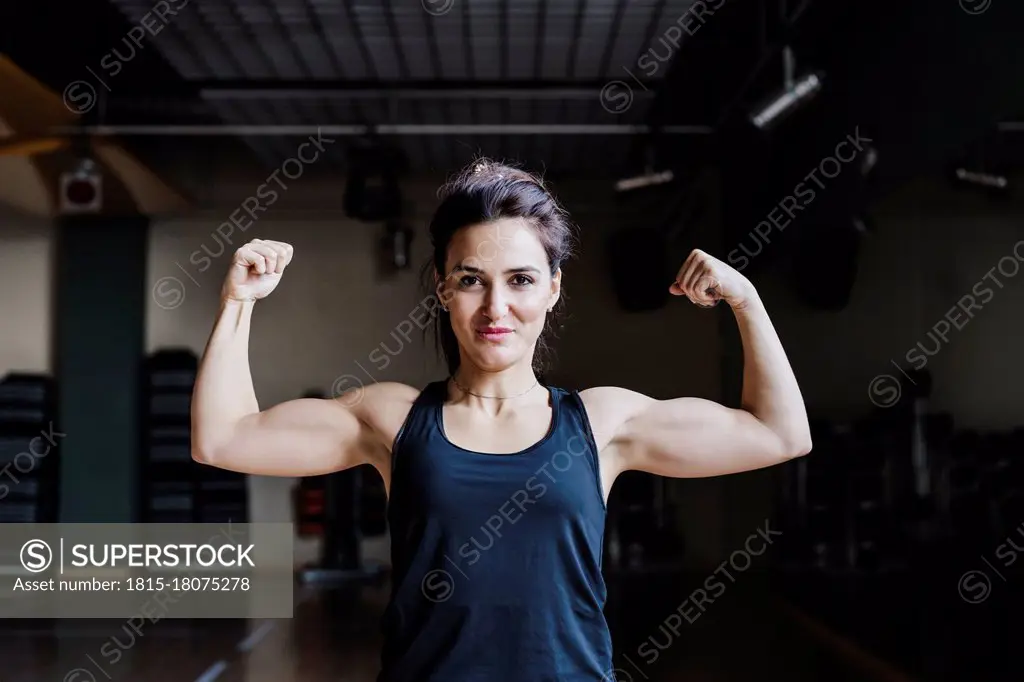 Beautiful female athlete flexing muscles in gym