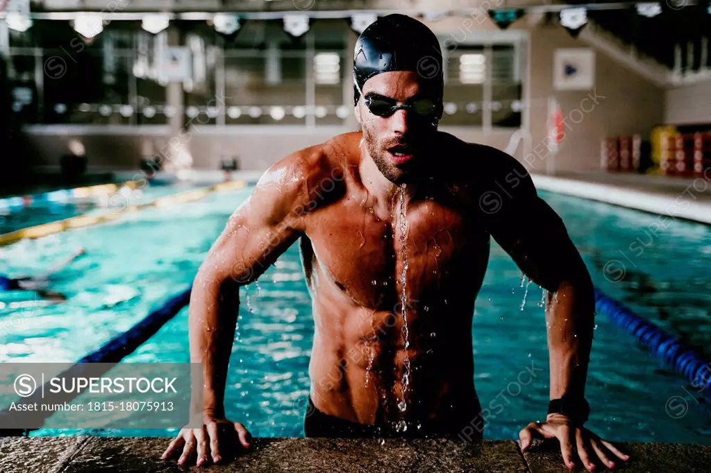 Professional muscular male swimmer getting out of pool