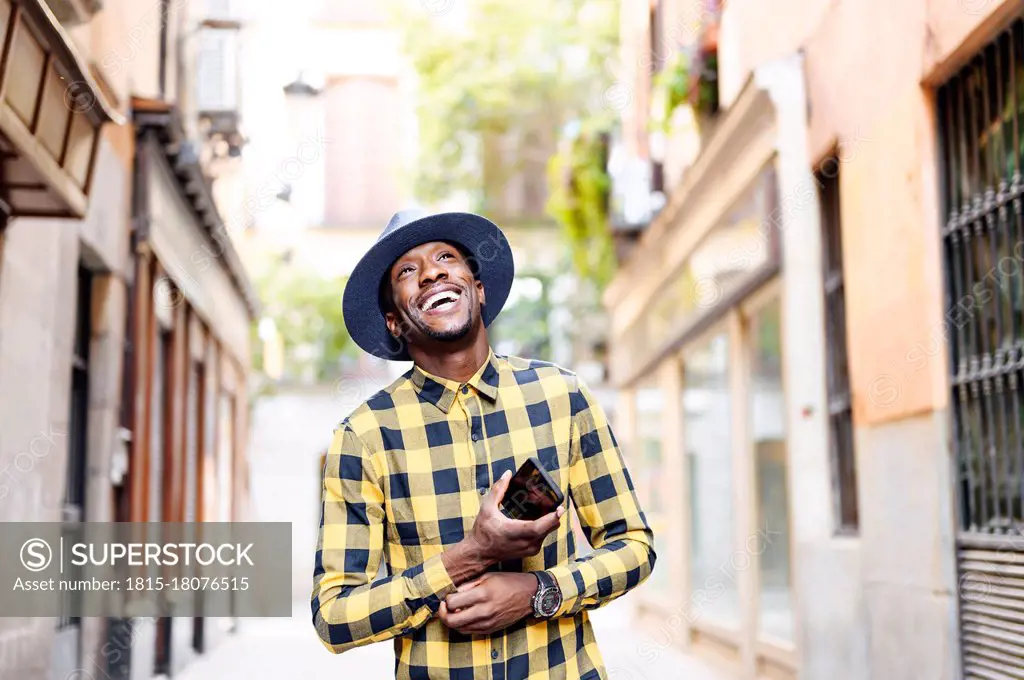 Smiling african man with smart phone looking away in city