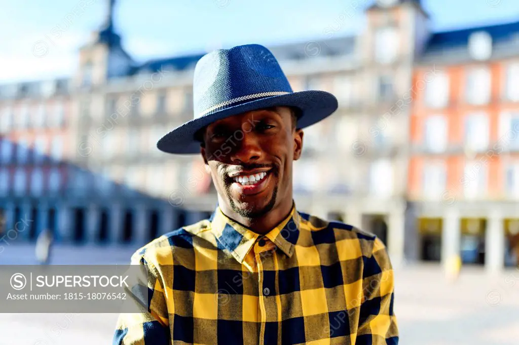 Smiling african man wearing hat while standing in city