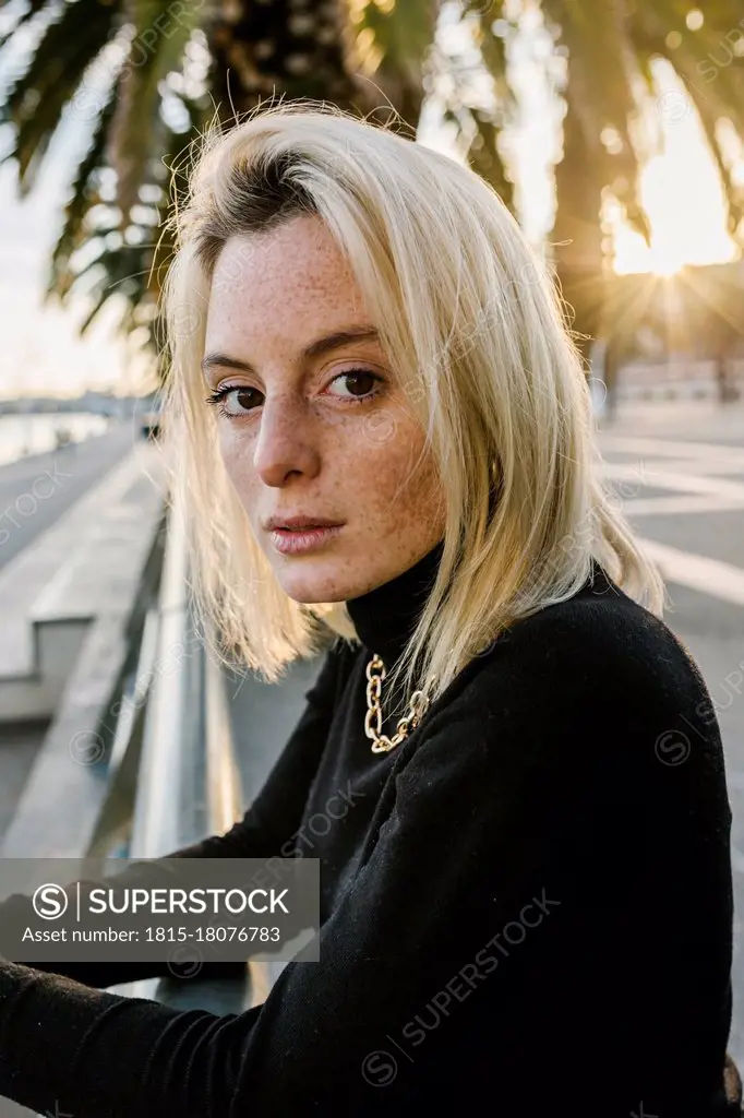 Young woman with medium length hair leaning on railing at promenade