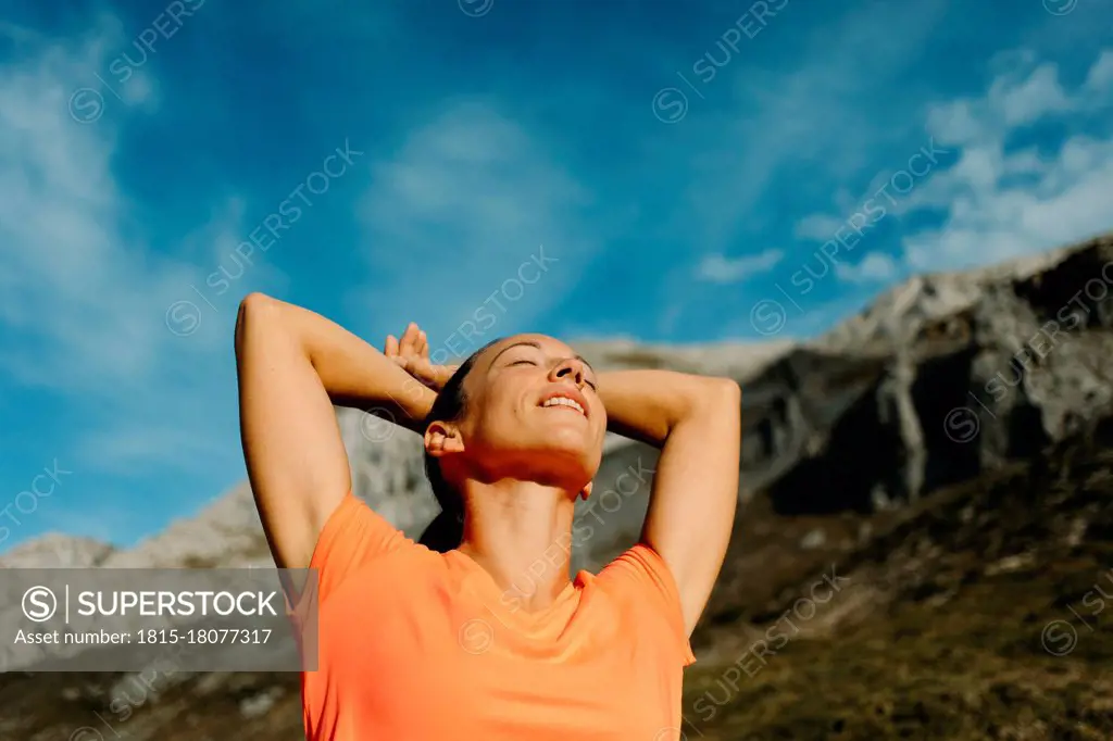 Explorer standing with hands behind head against sky at Cares Trail in Picos De Europe National Park, Asturias, Spain