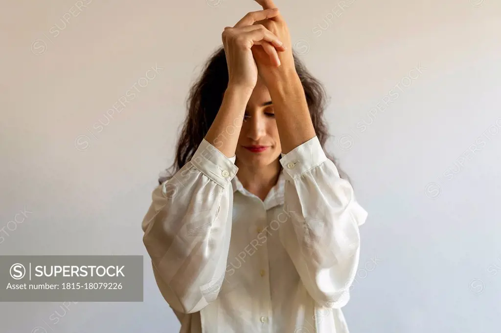 Female model posing with hands clasped against wall