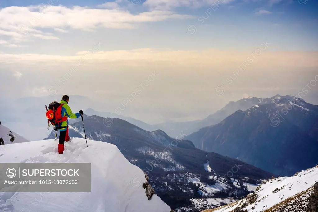 Male alpinist admiring view while standing on snowcapped mountain