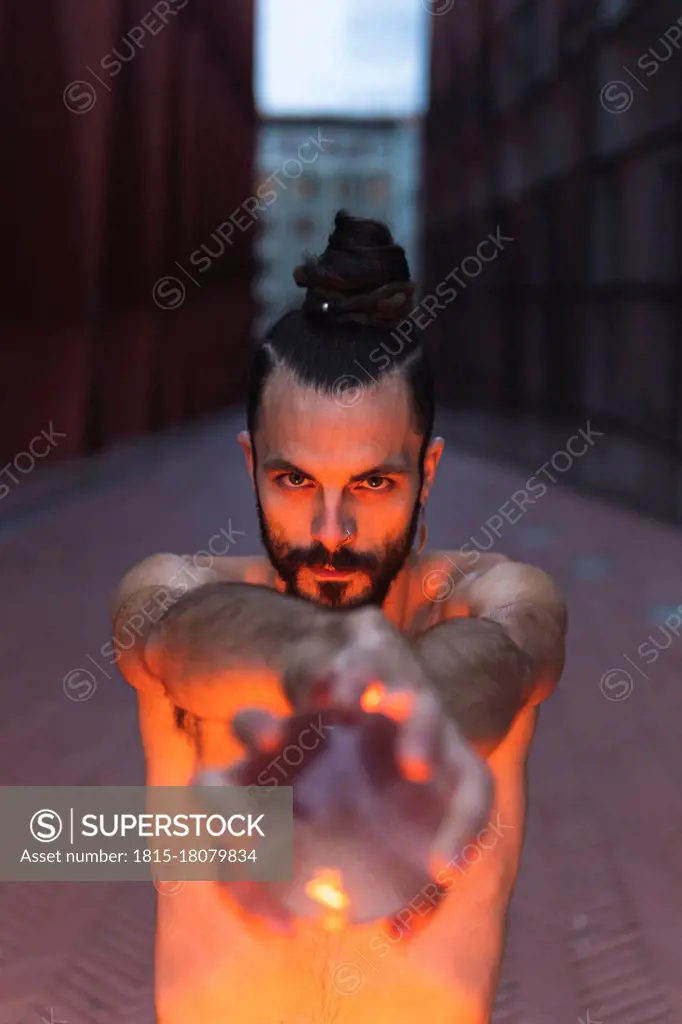 Man performing with acrylic ball on footpath at dusk