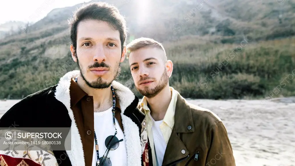 Homosexual couple standing against mountain at beach during vacations