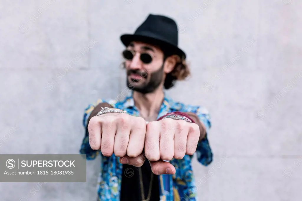 Caucasian man showing knuckles while standing in front of wall