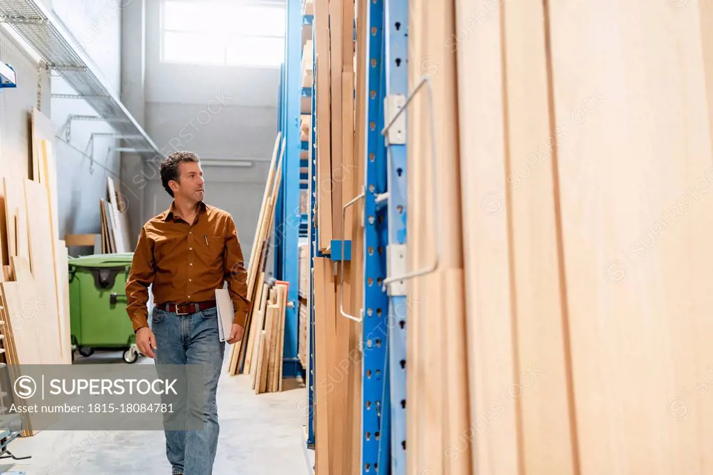 Carpenter examining shelves with planks of wood