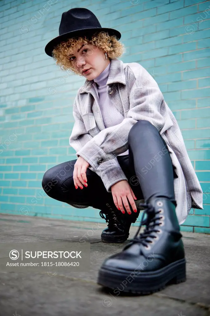 Woman in hat squatting on footpath