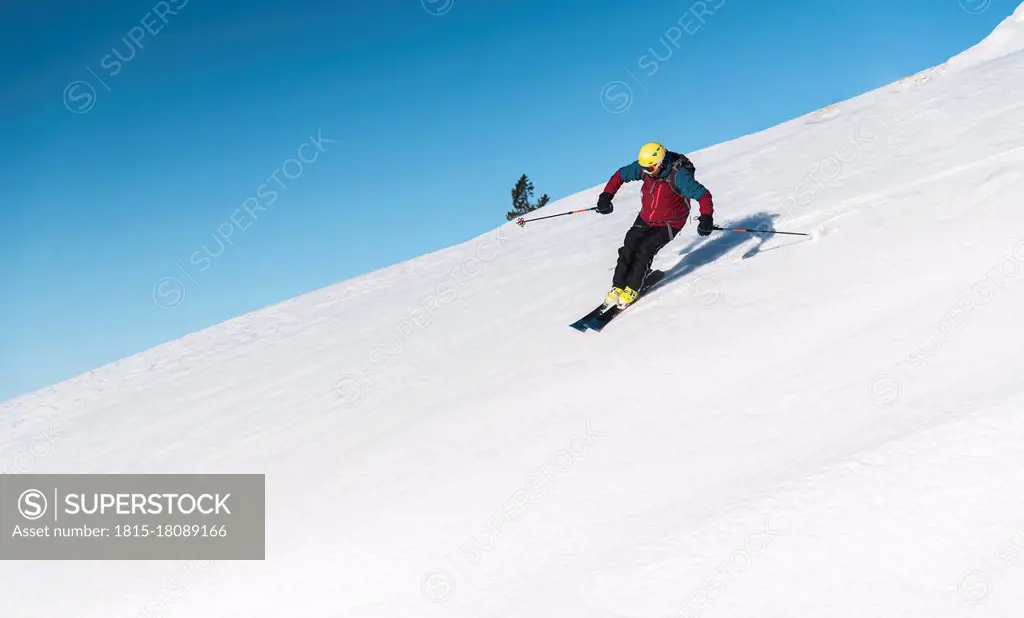 Mature man skiing on mountain slope against sky