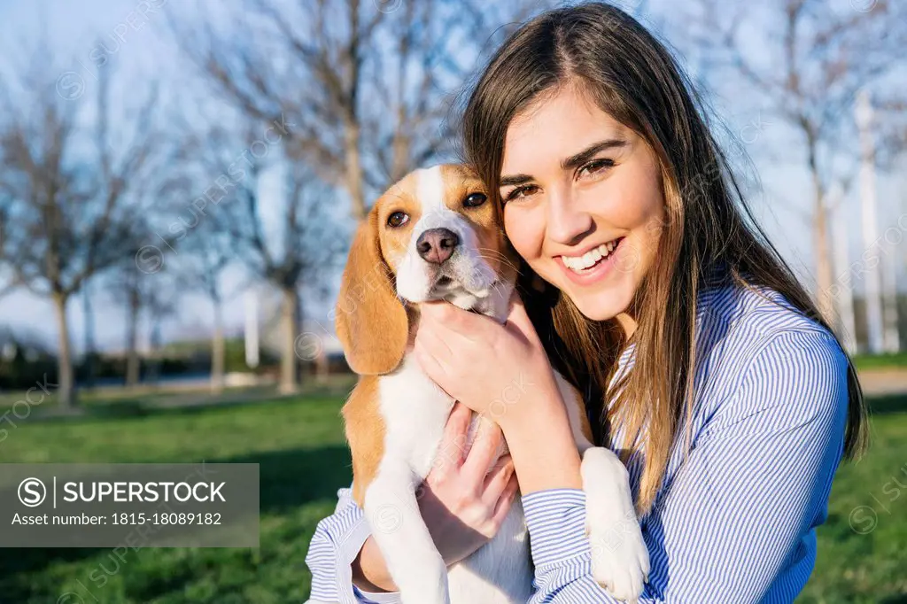 Female pet owner smiling while embracing dog at park