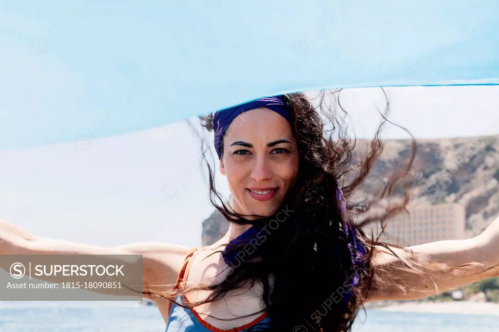 Smiling dancer holding blue sarong on sunny day