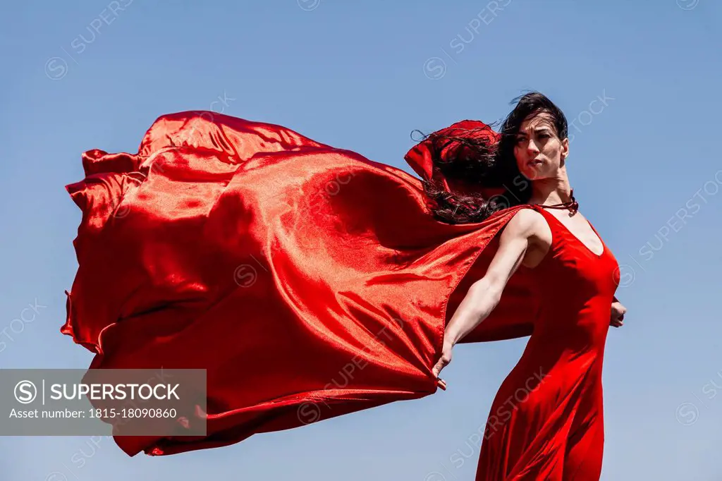 Beautiful female dancer with red scarf looking away against clear sky on sunny day