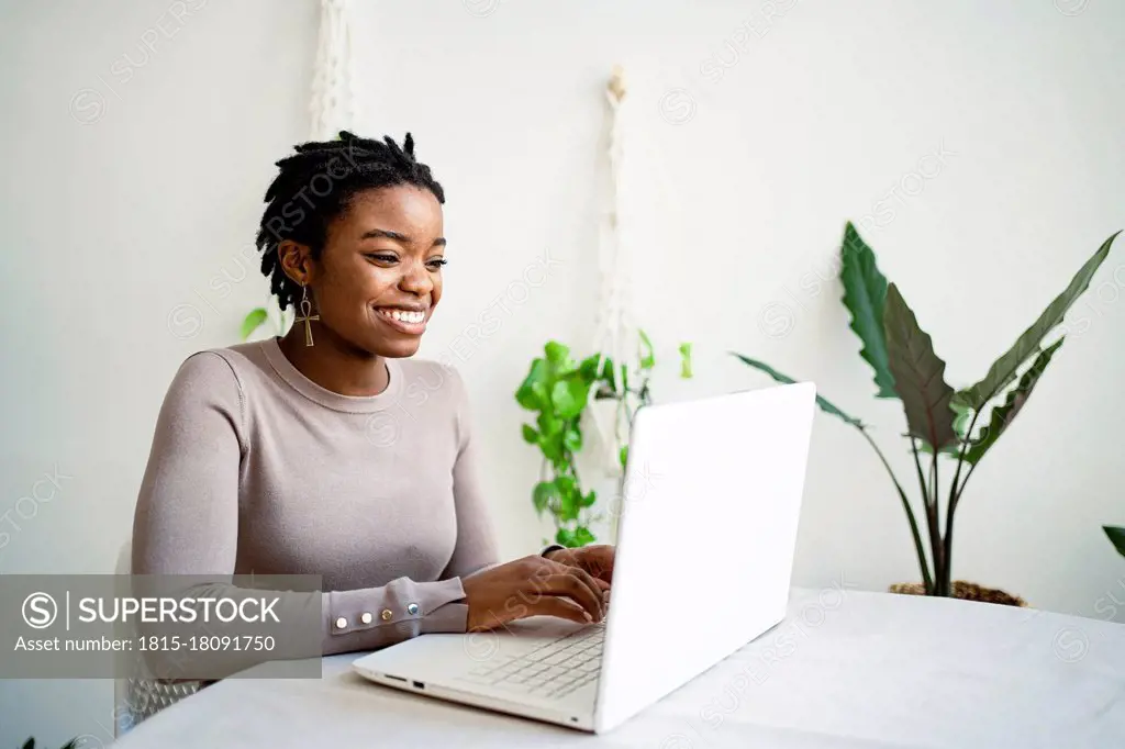 Young female entrepreneur working on laptop in living room