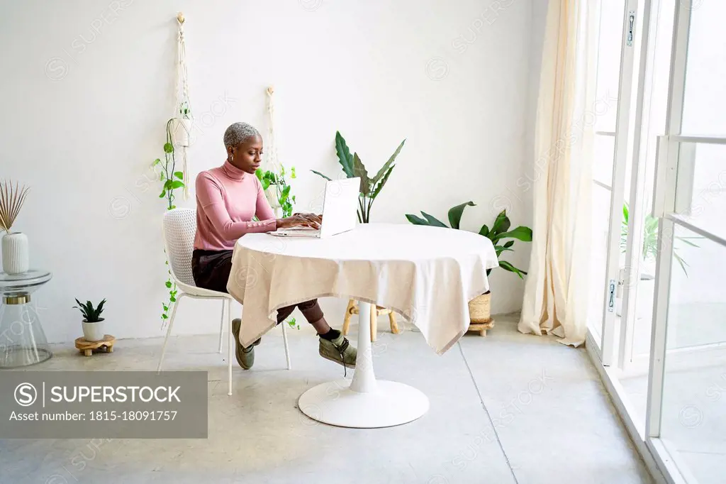 African businesswoman working on laptop in living room