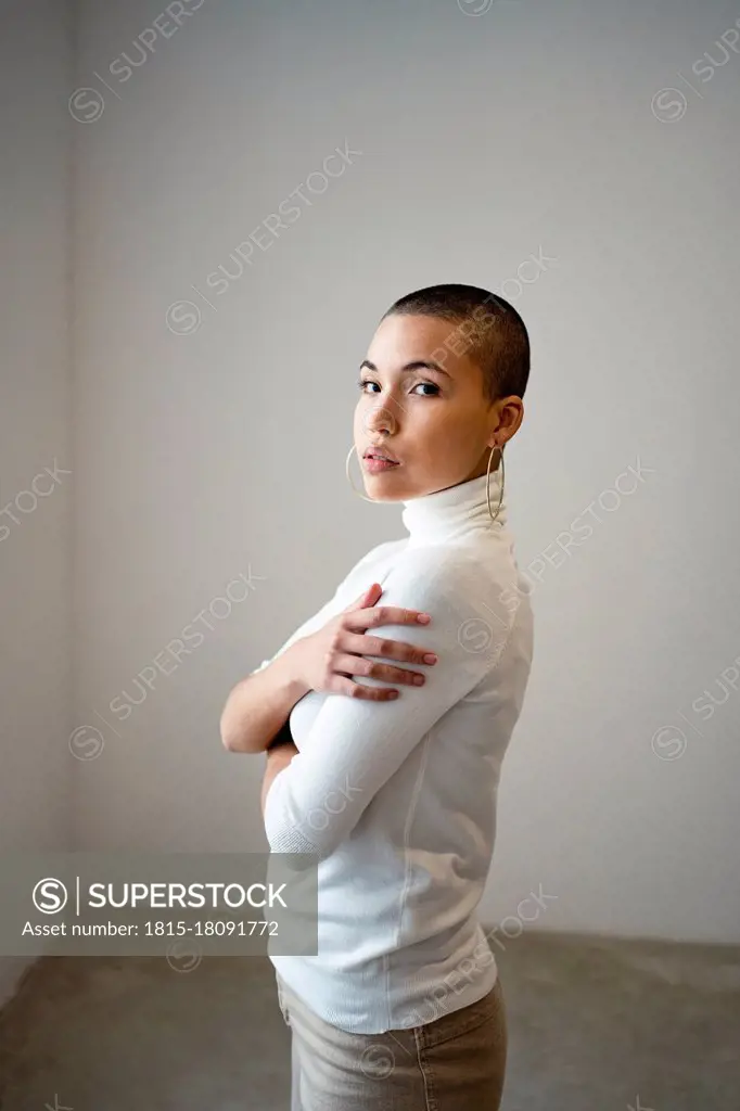 Confident woman with arms crossed at home