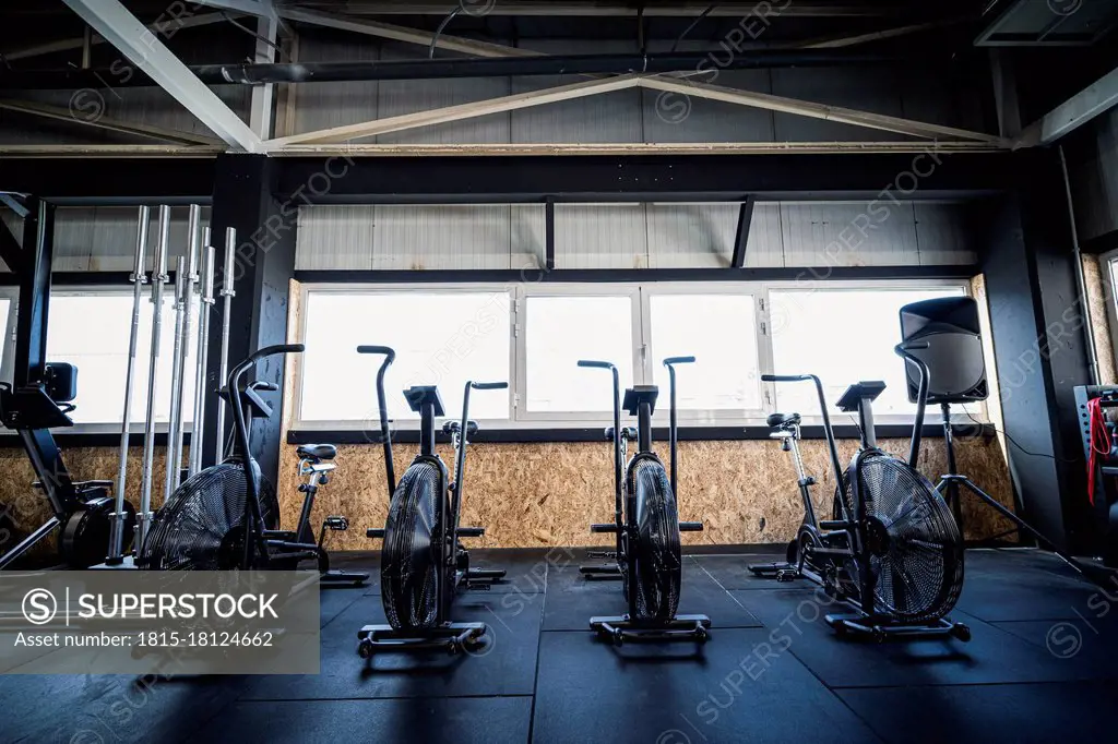 Row of exercise bikes standing in empty gym