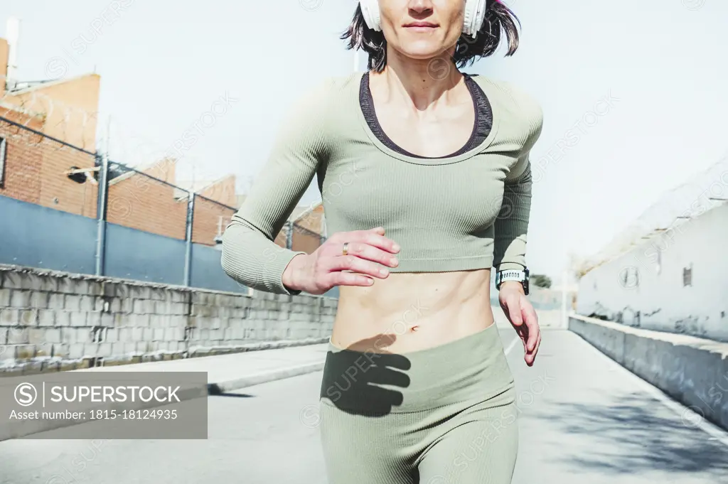 Woman in sports clothing running against sky