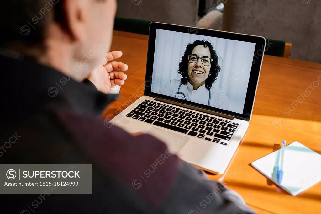 Smiling female doctor on video call consultation with senior male patient at home Covid-19