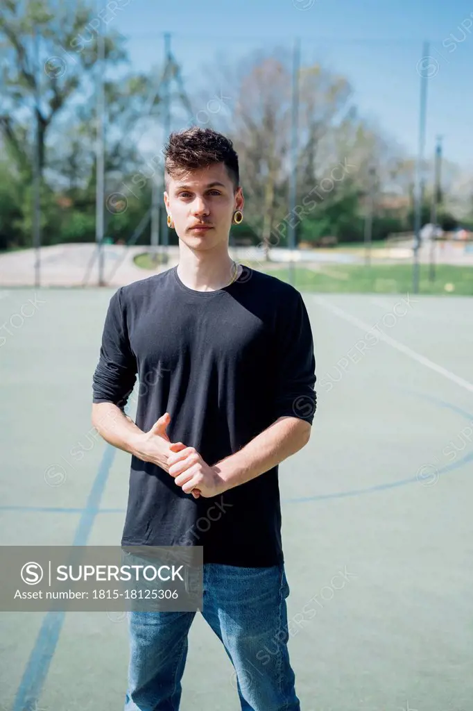 Young hipster man standing at sports court during sunny day