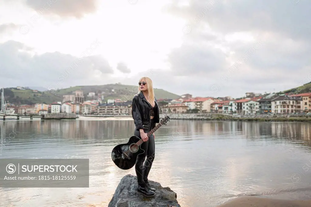 Beautiful woman looking away while standing on rock at lake