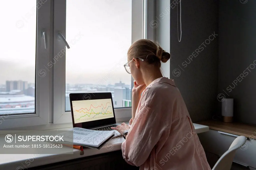 Woman working on laptop while sitting at home office