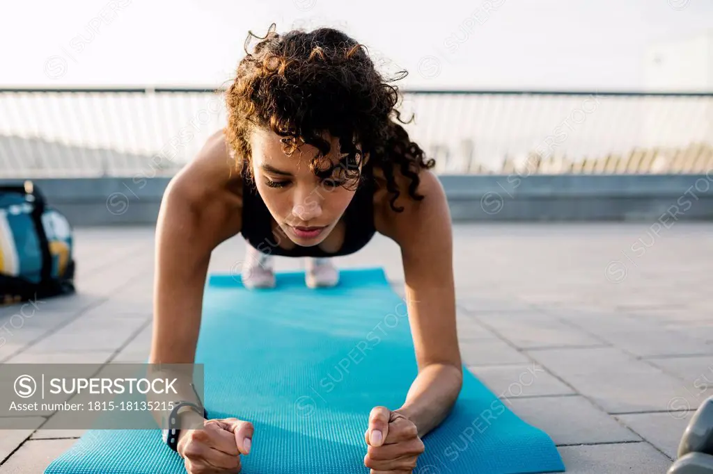 Female athlete exercising in plank position on exercise mat