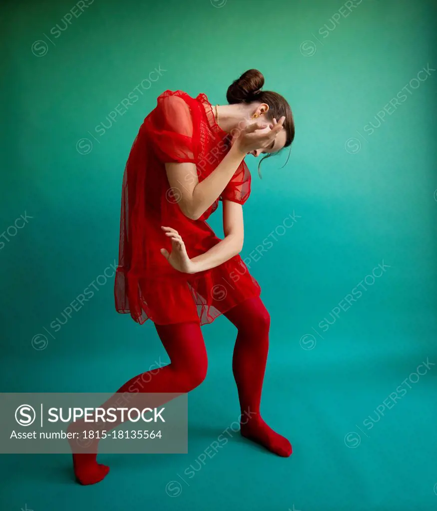 Female ballet dancer dancing against turquoise background