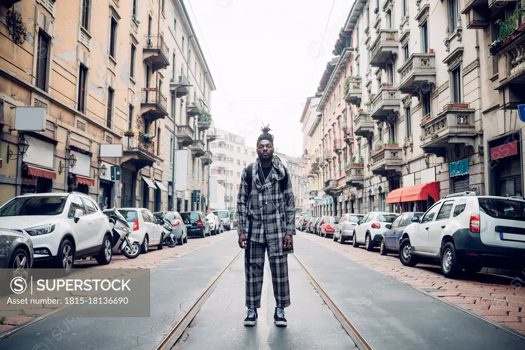 Young fashionable man standing on tramway in city