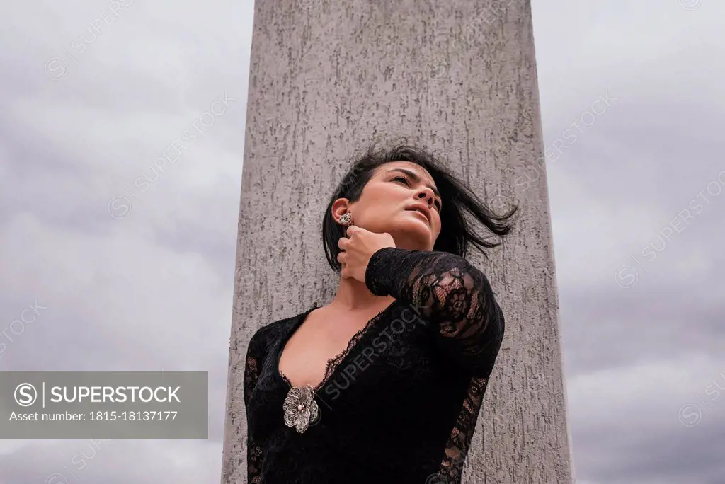 Thoughtful woman looking away while standing in front of architectural column