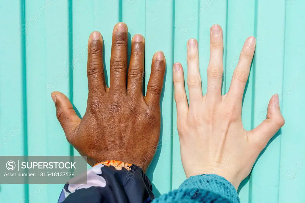 Hands of multi-ethnic male and female friends on turquoise wall