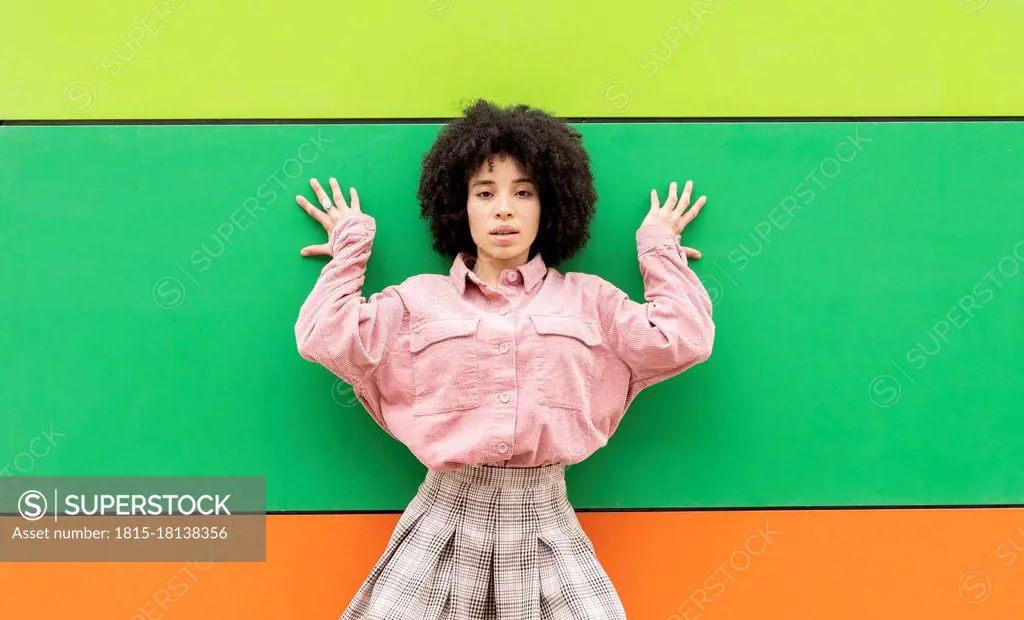 Curly hair woman leaning on colorful wall