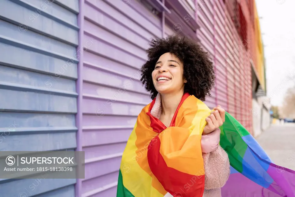 Cheerful woman wrapped in rainbow flag