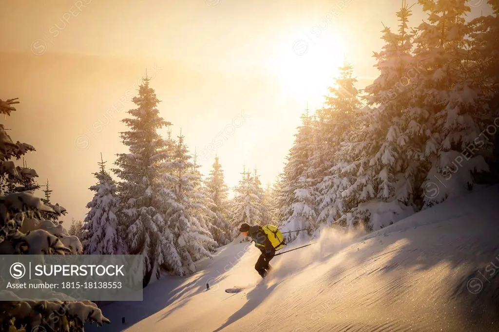 Mid adult man skiing on snowy mountain during sunrise