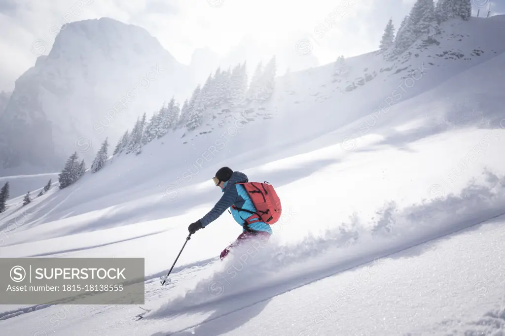 Mid adult woman skiing on snowcapped mountain during sunny day