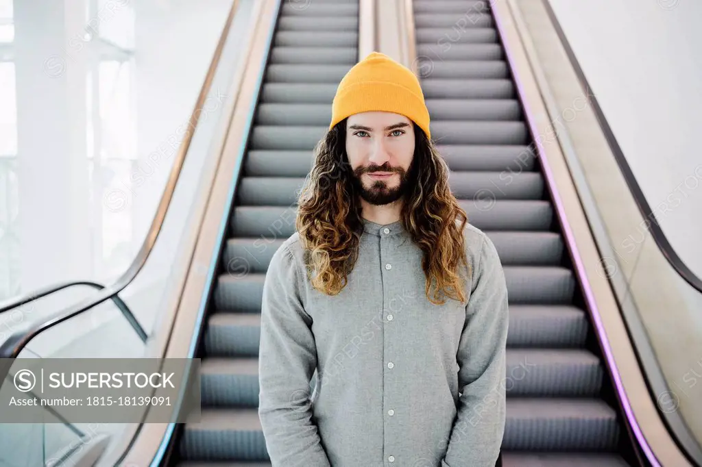 Handsome man in knit hat standing in front of escalator