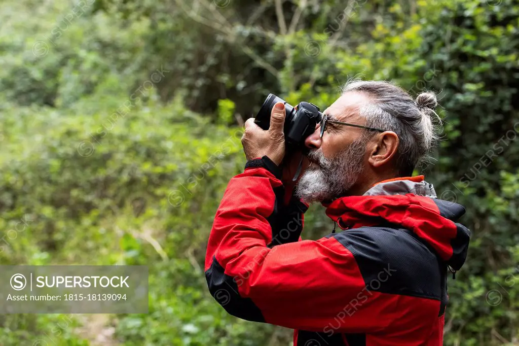 Male explorer photographing in forest