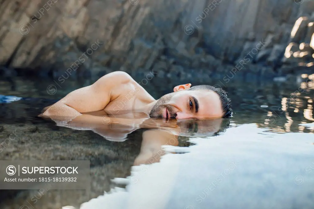 Shirtless man floating on water during vacations