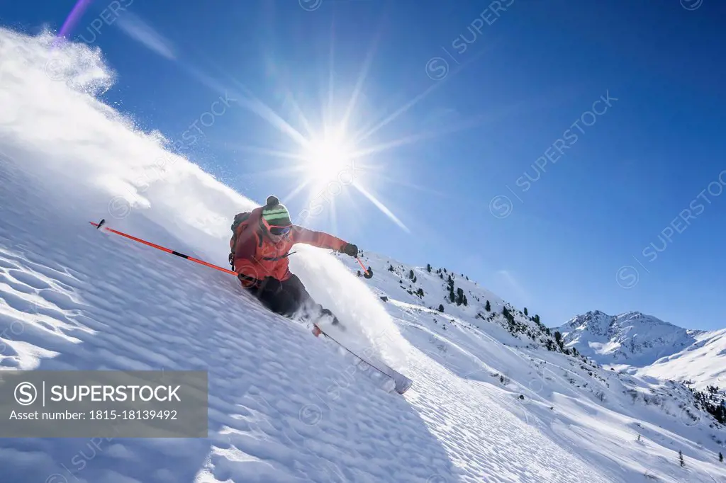 Sun shining over man skiing in¶ÿArlberg¶ÿmassif