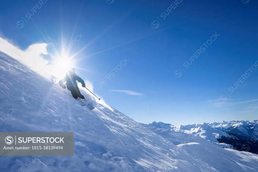 Sun shining over man skiing in¶ÿArlberg¶ÿmassif