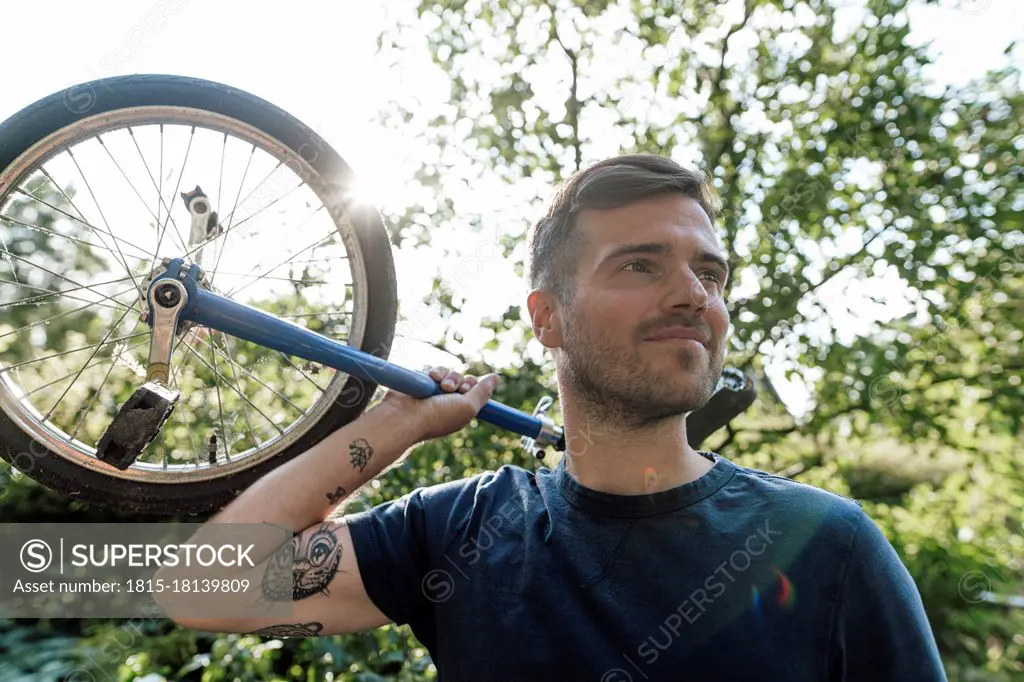 Man with unicycle looking away during sunny day